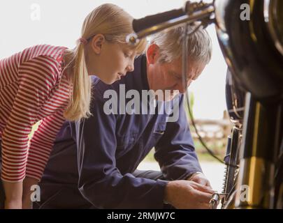 Junges Mädchen hilft Großvater Motorrad zu reparieren Stockfoto