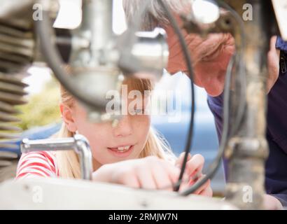 Junges Mädchen hilft Großvater Reparatur Motorrad Motor Stockfoto