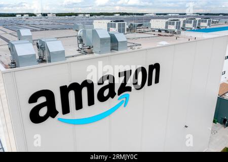 28. August 2023, Niedersachsen, Großenkneten: Das Amazon-Logo hängt am neuen Logistikzentrum des Unternehmens am ehemaligen Luftwaffenstützpunkt Ahlhorn (Luftaufnahme mit Drohne). Bis Ende des Jahres sollen auf der neuen Website des Online-Einzelhändlers rund 1.000 Arbeitsplätze geschaffen werden. Foto: Hauke-Christian Dittrich/dpa Stockfoto