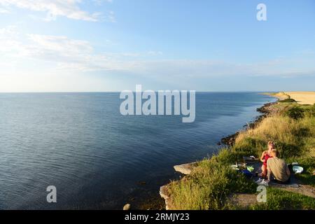 Ein dänisches Paar genießt sein Picknick auf der Klippe mit Blick auf die wunderschöne Küstenlandschaft am Großen Gürtel in Korsør, Dänemark. Stockfoto
