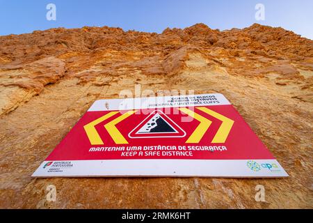 FELSSTURZ INSTABILE KLIPPEN, HALTEN SIE Einen SICHEREN ABSTAND ist in englischer Sprache auf einem Warnschild in Portugal auf den Klippen des Atlantischen Ozeans geschrieben. Felsen und Stockfoto