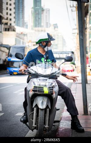 Ein thailändischer Mann hält an der Phetchaburi Rd Bangkok, Thailand auf seinem Motorrad, mit einem Helm im Polizeistil. Stockfoto