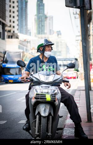 Ein thailändischer Mann hält an der Phetchaburi Rd Bangkok, Thailand auf seinem Motorrad, mit einem Helm im Polizeistil. Stockfoto