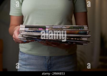 Eine Frau stapelt alte Zeitungen in einem Stapel, Altpapier sammelt. Vorbereitung von Papierabfällen für das Recycling. Stockfoto