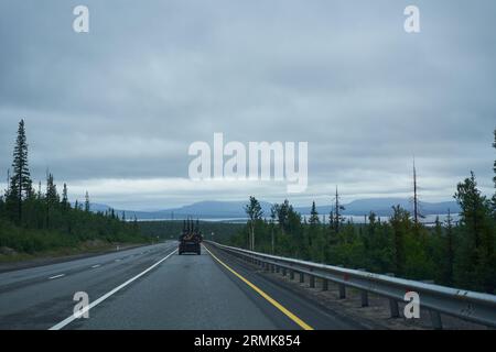 Ein Auto mit vielen Fahrrädern, die an das Dach und den Kofferraum angeschlossen sind, fährt auf einer von Bäumen umgebenen Straße. Reisen mit Fahrrädern Stockfoto