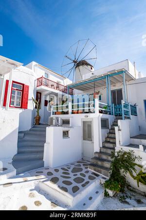 Weiße kykladische Häuser mit bunten Fensterläden, Bonis Windmühle auf der Rückseite, Gassen der Altstadt von Chora, Mykonos Stadt, Mykonos, Kykladen, Griechenland Stockfoto