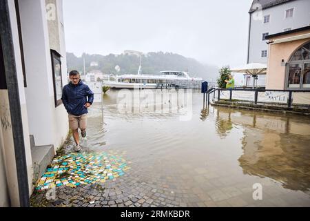 Passau, Deutschland. 29. August 2023. Ein Passant wühlt durch das Wasser in der Passauer Altstadt. Am Ort überfließt die Donau ihre Ufer mit einer Höhe von 8,00 Metern. Die für die Donau in der Nacht prognostizierte Stufe 4 (8,50 Meter) wurde nicht erreicht. Er hatte den Gipfel mit acht Metern bei etwa zehn Uhr erreicht und ist seither leicht zurückgegangen. Tobias C. Köhler/dpa/Alamy Live News Stockfoto