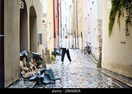 Passau, Deutschland. 29. August 2023. Die Bewohner schützen ihre Häuser in der Höllgasse in der Passauer Altstadt mit Sandsäcken und Planen. Der mobile Hochwasserschutz, bestehend aus Metallsegmenten, wurde bereits installiert. Die für die Donau in der Nacht prognostizierte Stufe 4 (8,50 m) wurde nicht erreicht. Sie hatte gegen zehn Uhr einen Höchststand von acht Metern erreicht und ist seither leicht zurückgegangen. Tobias C. Köhler/dpa/Alamy Live News Stockfoto