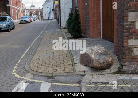 Moot Stone, außerhalb eines modernen Hauses, das auf und um die Basis eines alten Hauses an der Ecke von St Thomas Street und Minster Lane gebaut wurde. Bild entlang der St. Thomas Street. Winchester, Hampshire, England 2023. Stockfoto