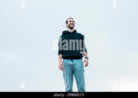 Lächelnder Porträtmann, der am blauen Himmel steht Stockfoto