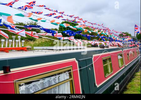 Bunting besteht aus kleinen Flaggen, die auf einem Schmalboot auf einem Kanal im Wind flattern. Stockfoto