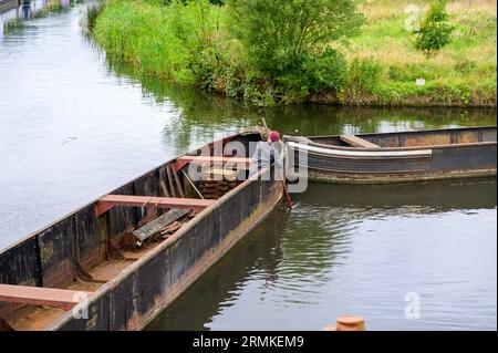 Schleppen Sie leere historische Lastenschmalboote, die von Bug zu Bug entlang des Kanals bewegt werden und versuchen, eine Kurve zu biegen. Stockfoto