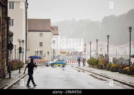 Passau, Deutschland. 29. August 2023. Die Donau überfließt mit einer Höhe von 8,00 Metern das Ufer der Fritz-Schäffer-Promenade. Die Polizei schließt die Straße für Passanten und Fahrzeuge ab. Die für die Donau in der Nacht prognostizierte Stufe 4 (8,50 Meter) wurde nicht erreicht. Sie hatte gegen zehn Uhr einen Höchststand von acht Metern erreicht und ist seither leicht zurückgegangen. Tobias C. Köhler/dpa/Alamy Live News Stockfoto