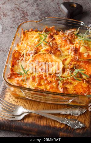 Süßkartoffelauflauf mit Cheddar-Käse und Rosmarin in Glasform auf dem Tisch. Vertikal Stockfoto