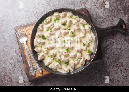 Gebratene und dann gedünstete Hühnerherzen in einer cremigen Sauce mit aromatischen Kräutern aus nächster Nähe auf einem Teller auf dem Tisch. Horizontale Draufsicht von oben Stockfoto