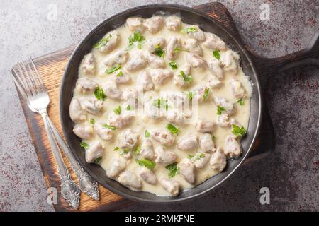 Rustikale Art gedünstete Hühnerherzen in Sauerrahm mit aromatischen Kräutern aus der Nähe auf einem Teller auf dem Tisch. Horizontale Draufsicht von oben Stockfoto