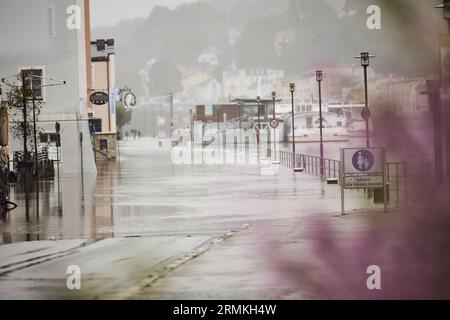 Passau, Deutschland. 29. August 2023. Die Donau überfließt mit einer Höhe von 8,00 Metern das Ufer der Fritz-Schäffer-Promenade. Die Polizei schließt die Straße für Passanten und Fahrzeuge ab. Die für die Donau in der Nacht prognostizierte Stufe 4 (8,50 Meter) wurde nicht erreicht. Sie hatte gegen zehn Uhr einen Höchststand von acht Metern erreicht und ist seither leicht zurückgegangen. Tobias C. Köhler/dpa/Alamy Live News Stockfoto