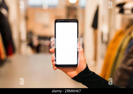 Nahaufnahme der Hand der Frau, die ihr Smartphone mit weißem Bildschirm zeigt Stockfoto