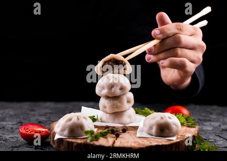 Hand halten Essstäbchen mit Knödel Stockfoto