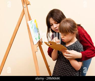 Side View Girl Help Girl with Down syndrome paint Stockfoto