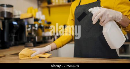 Seitenansicht Barista mit Reinigungstisch mit Latexhandschuhen Stockfoto