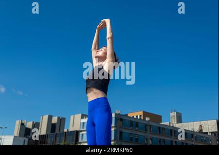 Die Frau streckt ihre Arme über ihren Kopf, während sie sich auf das Training vorbereitet Stockfoto