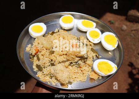 Edelstahlplatte mit Gemüse-Biryani und gekochten Eiern in der Hand. Besondere Speisen für besondere Anlässe Stockfoto