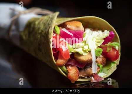 Hausgemachte vegane Tortillas mit roten Bohnen, Süßkartoffeln, Tomaten und Guacamole mit Saucen und Gewürzen auf schwarzem Hintergrund. Stockfoto