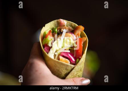 Hausgemachte vegane Tortillas mit roten Bohnen, Süßkartoffeln, Tomaten und Guacamole mit Saucen und Gewürzen auf schwarzem Hintergrund. Stockfoto