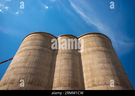 Drei Getreidesillos, die hochschauen, mit starkem Blickwinkel, vor einem blauen Himmel mit schroffen Wolken Stockfoto
