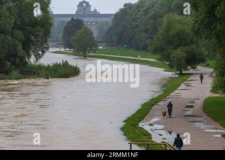 München, Deutschland. 29. August 2023. Passanten spazieren am Ufer der überfluteten Isar entlang, die durch die bayerische Hauptstadt fließt. Quelle: Peter Kneffel/dpa/Alamy Live News Stockfoto