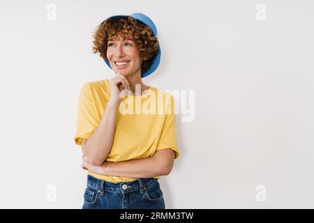 Ginger-Frau mittleren Alters, die panama lächelt, während sie isoliert über einer weißen Wand steht Stockfoto