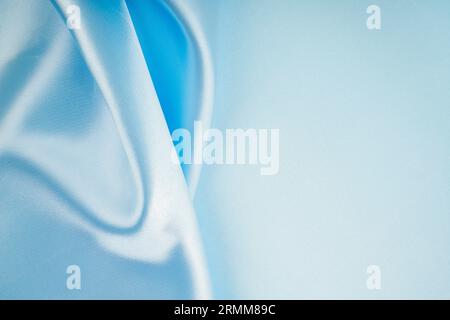 Weiche, wellige Falten aus hellblauem Seidensatin-Hintergrund mit Kopierraum für Ihr Design. Stockfoto