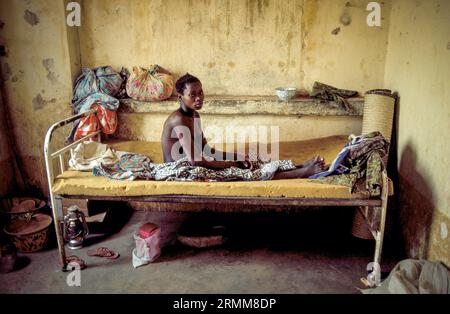 Mali. Kranke Frau sitzt in einer Dorfklinik auf ihrem Bett. Stockfoto