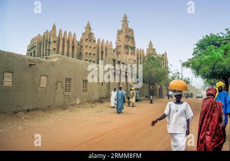 Mali, Mopti. Menschen, die an der traditionellen adobe-Moschee vorbeigehen. Stockfoto