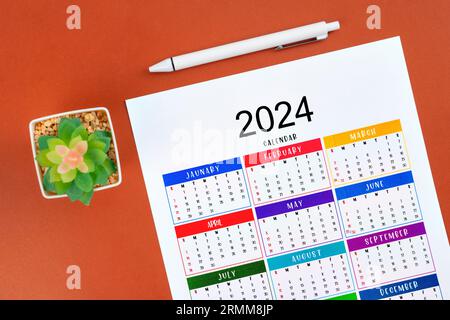 Kalender 2024 Seite und weißer Stift mit Pflanztopf auf schönem Hintergrund. Stockfoto