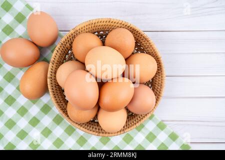 Frische Eier in einem Holzkorb und Tischdecke auf hölzernem Hintergrund. Stockfoto