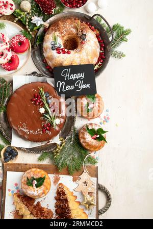 Verschiedene Desserts und Süßigkeiten für die Weihnachtsfeiertage auf weißem Hintergrund. Draufsicht. Bundt Cake, Schokoladenkuchen, Kekse und Donuts. Stockfoto