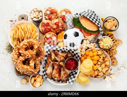 Tischszene mit einer großen Auswahl an Imbiss- und Fast Food-Gerichten. Hamburger, Pizza, gebratenes Huhn und Snacks auf weißem Hintergrund. Draufsicht. Stockfoto