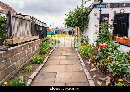 Kleine Häuser mit farbenfroher Dekoration in den Gärten im Fischerviertel Footdee, Aberdeen, Großbritannien. Stockfoto