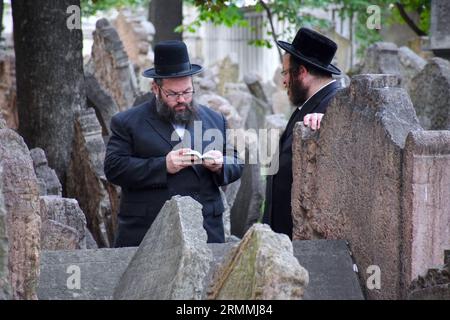 Der Alte jüdische Friedhof in Josefov, dem jüdischen Viertel, in Prag - Tschechische Republik. Einige traditionell gekleidete juden beten. Stockfoto