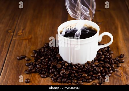 Tasse Espresso mit Bio-Kaffeebohnen auf altem Holztisch Stockfoto