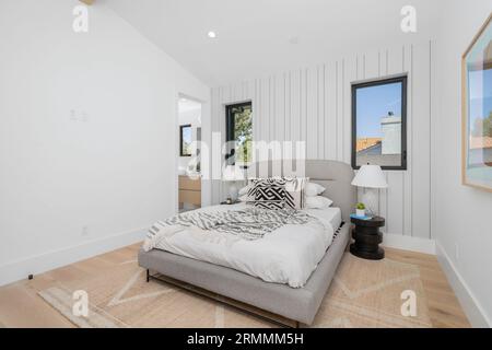 Eine moderne Hauptschlafzimmer-Inneneinrichtung verfügt über ein zeitgenössisches Tapetendesign sowie einen neuen Deckenventilator für zusätzliche Luftzirkulation Stockfoto