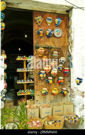 Frigiliana, farbenfrohe Ausstellung traditioneller spanischer Töpferwaren an einer sehr rustikalen Ladentür. Frigiliana, Provinz Malaga, Andalusien, Spanien. Stockfoto