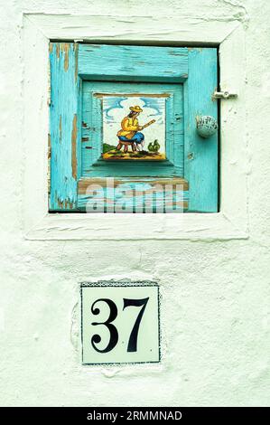 Ungewöhnliche malerische Miniatur-Tür in der Hausmauer. Frigiliana, Costa del Sol, Malaga, Andalusien, Spanien. Stockfoto