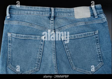 Rückansicht einer Jeans-Hose mit isolierten Taschen auf schwarzem Studiohintergrund Stockfoto