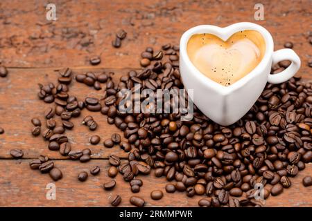 Tasse Espresso mit Bio-Kaffeebohnen auf altem Holztisch Stockfoto