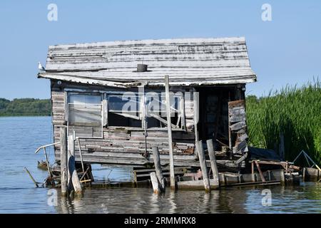 Verwitterte und verlassene Holzscheide auf dem Wasser Stockfoto