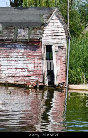 Verwitterte und verlassene Holzscheide auf dem Wasser Stockfoto