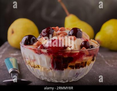 Schüssel mit gemischten Früchten, griechischem Joghurt und Honig, garniert mit Nüssen in einer Glasschale. Stockfoto